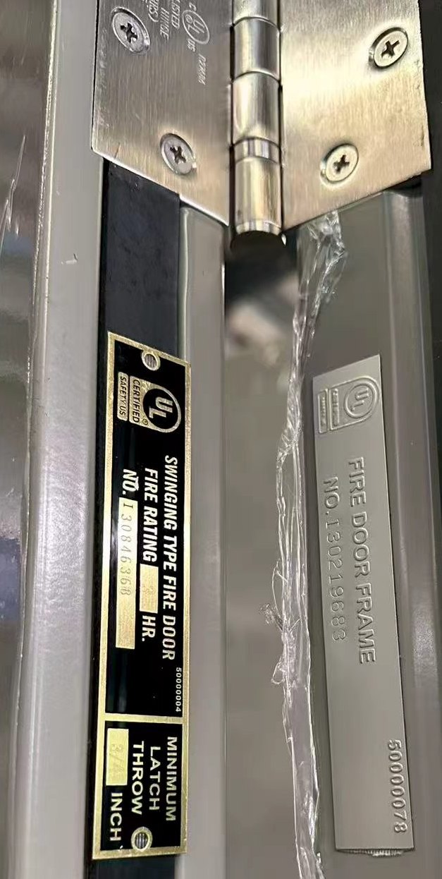 UL label on a fire door leaf beside the UL fire door frame plate and a listed hinge
